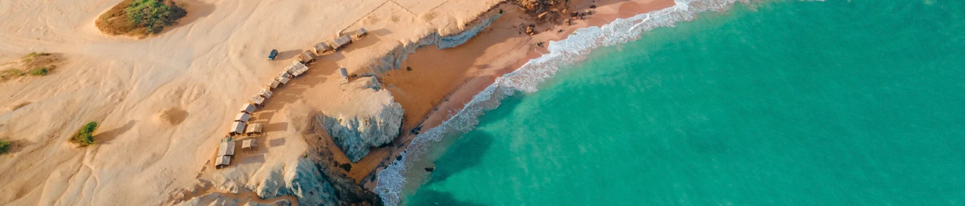 Larga playa con casas, el mar azul y el desierto ubicado en la Guajira, Colombia